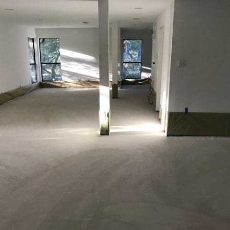 A room featuring concrete floors and a large window allowing natural light to enter.