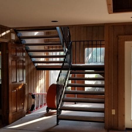 A wooden stairway in a home, featuring rich wood paneling and a closed door at the top.