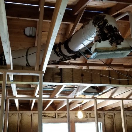 A ceiling fan and exposed ductwork are visible in a room, showcasing the room's ventilation and cooling features.